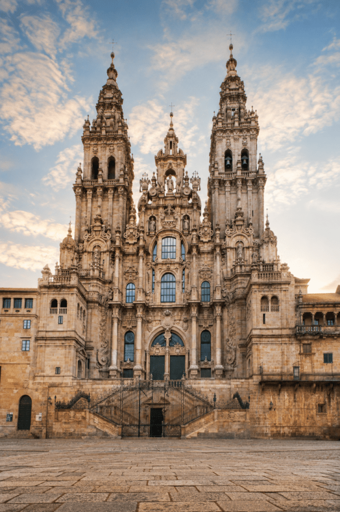Catedral de Santiago de Compostela con su fachada barroca y las torres elevándose sobre la plaza del Obradoiro en una luz cálida de atardecer.