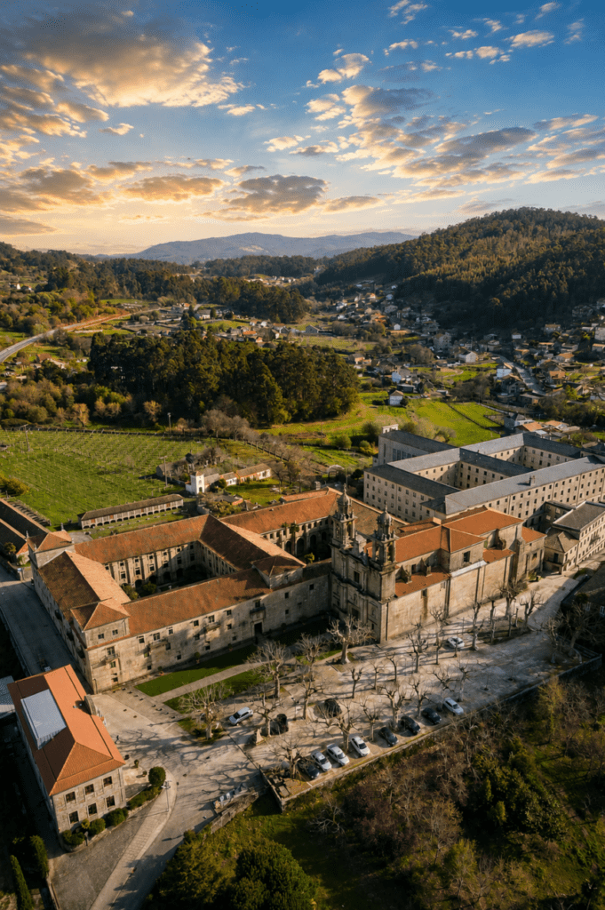 Vista aérea del Monasterio de Poio al atardecer, rodeado de bosques y colinas verdes en las Rías Baixas de Galicia.