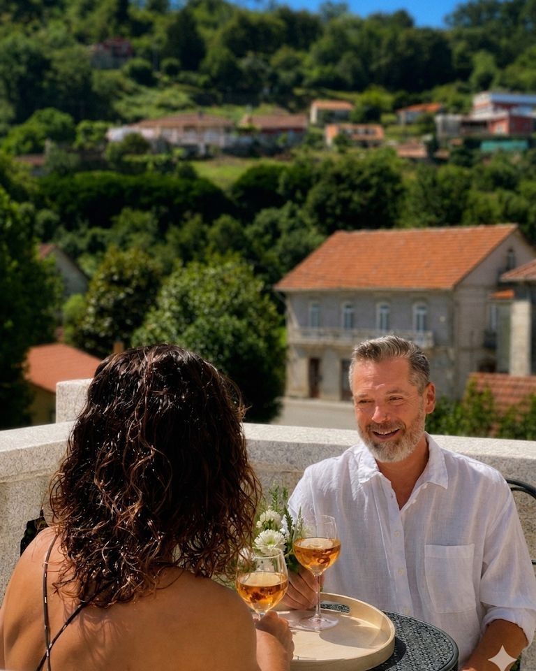 Pareja disfrutando de una copa de vino con vistas a los bosques y al río en Villa Boutique 1880, en Gaxate, A Lama.