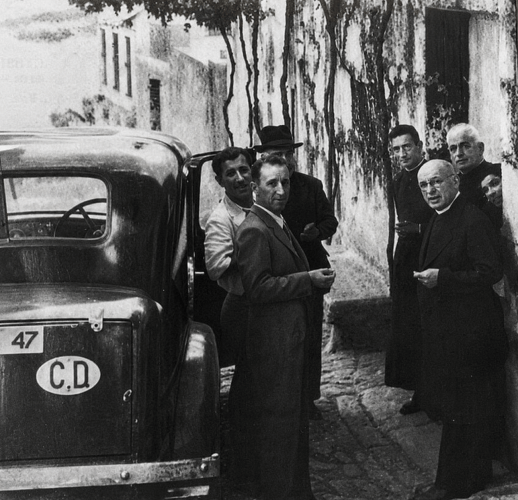 En esta iFotografía de época en la que aparecen varios miembros de la familia Camiña junto al médico Eduardo Martínez Alonso. A la derecha se encuentran tres sacerdotes: don Rogelio Camiña Garrido; su hermano, don Álvaro Camiña Garrido; y don Arturo Camiña, sobrino de ambos y posteriormente sacerdote en Verducido. A la izquierda, junto al automóvil, aparecen tres hombres: en primer término, un hombre vestido con traje cuya identidad desconocemos; detrás de él, con camisa blanca, Eduardo Martínez Alonso, médico vigués y agente 055A de los servicios secretos británicos; y, al fondo, un tercer hombre cuya identidad tampoco hemos podido determinar.